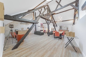 Ein geräumiges Loft mit freiliegenden Holzbalken, einer Steinwand und einem modernen Essbereich.