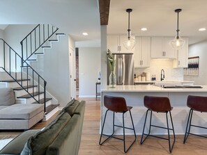 A modern kitchen with a central island, stainless steel appliances, and pendant lighting. - Bungalow Oasis! Central to Beaches for Groups w/ Firepit, Yard & Outdoor Shower (Wilmington)