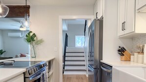 Eine moderne Küche mit Edelstahlgeräten, Holzböden und einer Treppe, die in eine andere Ebene führt.