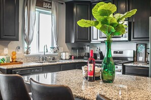 A kitchen with dark cabinets, a granite countertop, a green plant in a vase, and a wine bottle. - Matta Dr Escape >Massage Table, Wine Game Room & HotTub< (Colorado Springs)