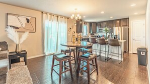 Een moderne keuken met donkerhouten kastjes, een roestvrijstalen koelkast en een eethoek met een ronde tafel en barkrukken.