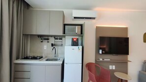 A compact kitchen with a gas stove, sink, microwave, and a refrigerator. - Mila Rooftop - Praia de Tamandaré (Tamandaré)