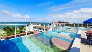 A rooftop infinity pool with a view of the ocean and palm trees. - Mila Rooftop - Praia de Tamandaré (Tamandaré)