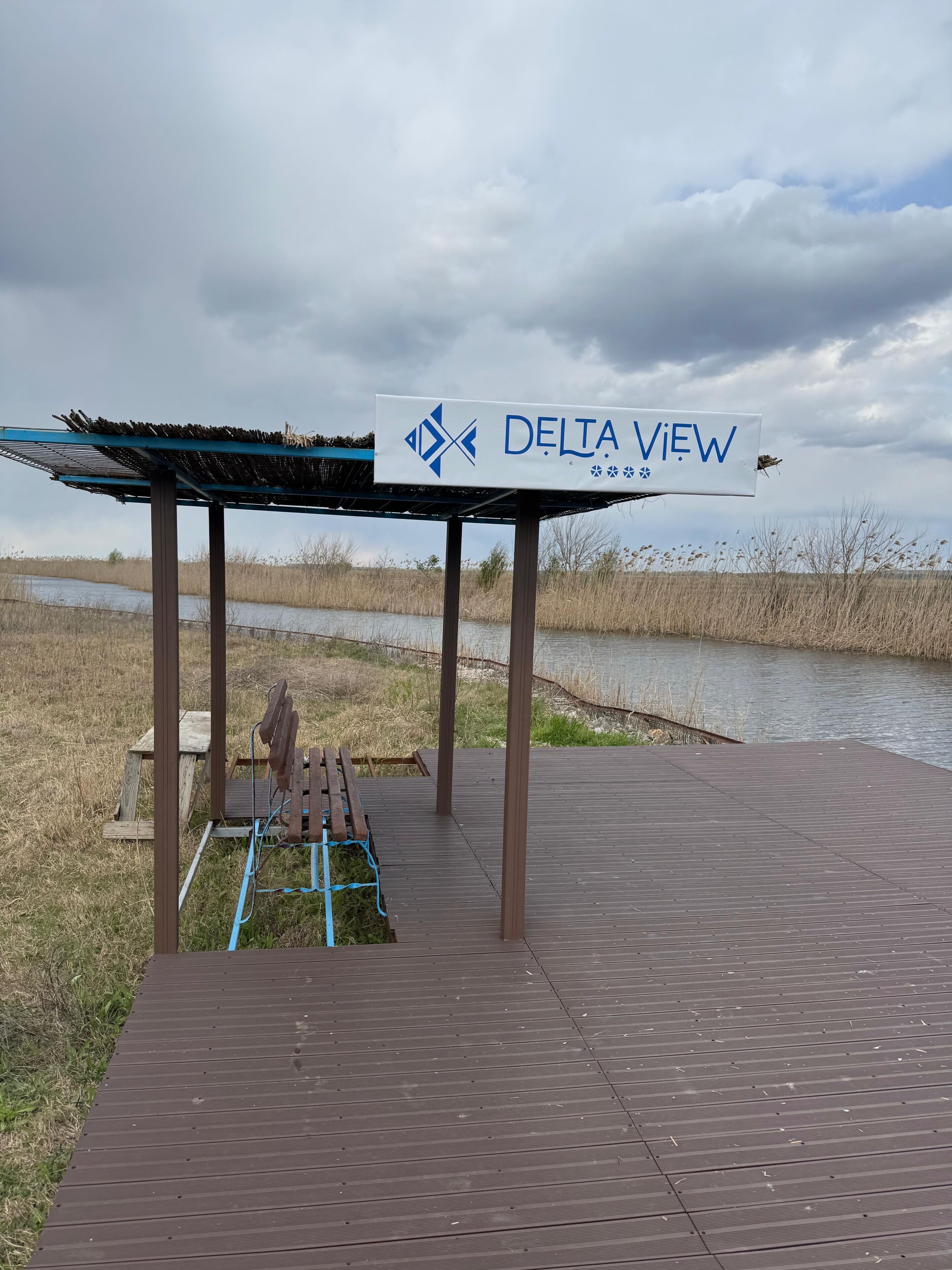 Una terraza de madera con un letrero que dice 'DELTA VIEW' y un banco.