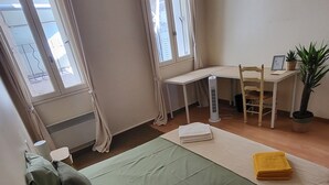 Ein Zimmer mit einem Bett, einem Schreibtisch, einem Stuhl und einer Topfpflanze.