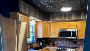 Una cocina con armarios de madera, un refrigerador de acero inoxidable, un microondas y una estufa.