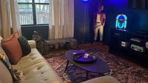 Una sala de estar con un sofá de cuero, una mesa de centro, un televisor y un letrero de neón.