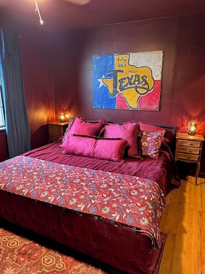 Ein Schlafzimmer mit einem großen Bett, einer Wandmalerei von Texas, zwei Nachttischen mit Lampen und einem gemusterten Teppich.