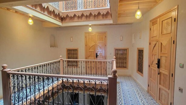 A spacious interior with a wooden staircase, ornate doors, and patterned flooring.