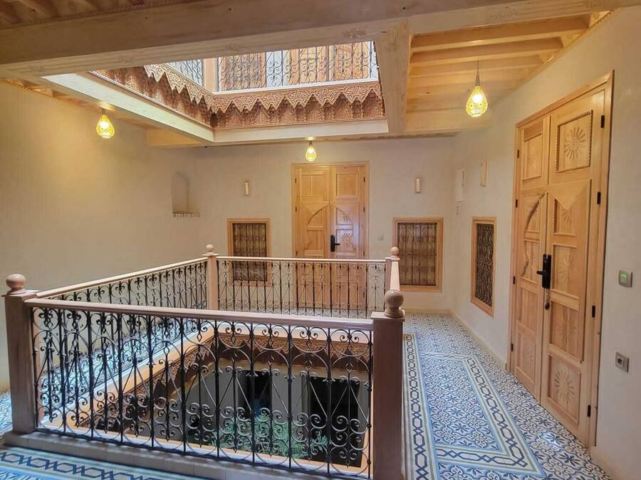 A spacious interior with a wooden staircase, ornate doors, and patterned flooring.
