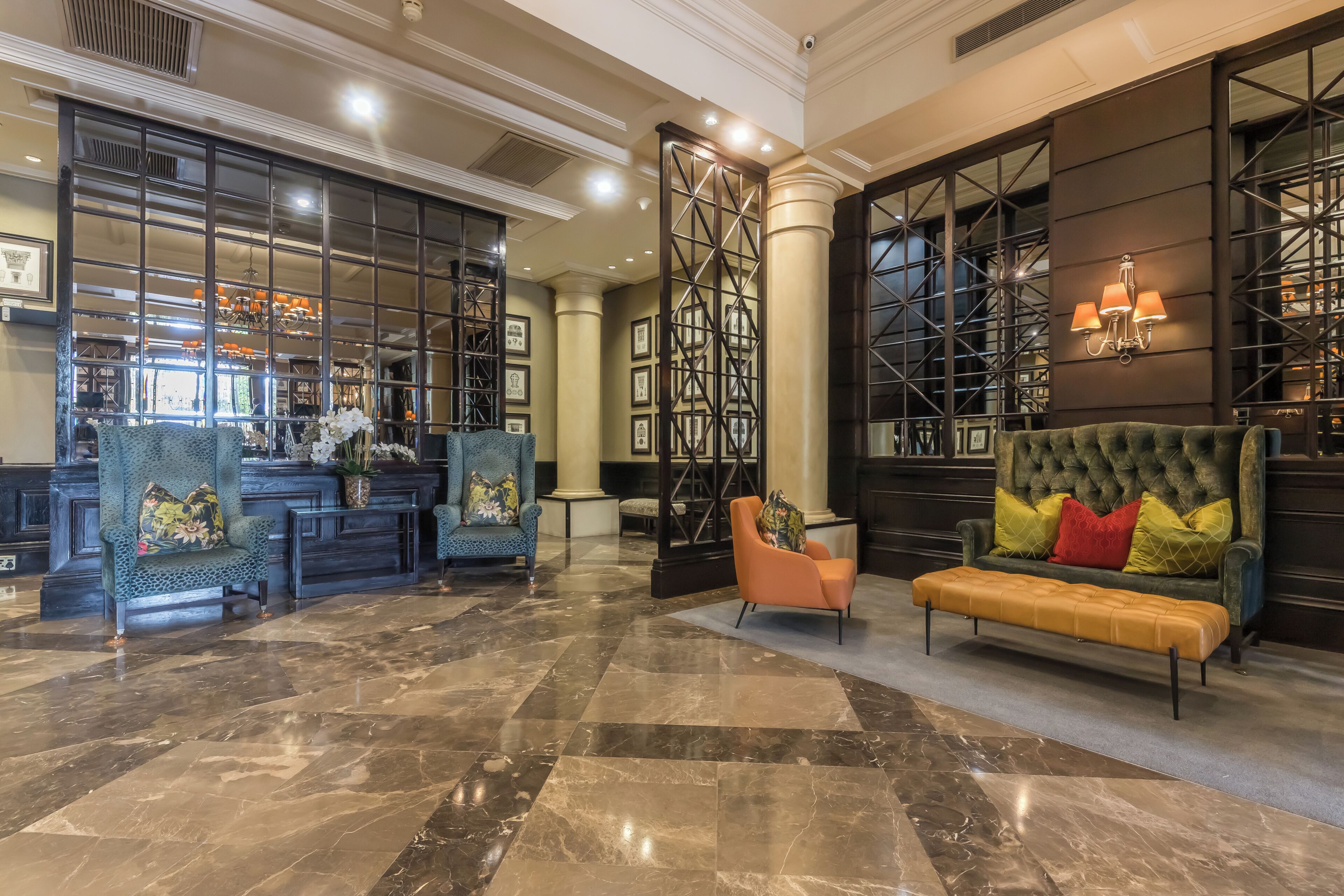 A lobby with a marble floor, a reception desk, and seating areas including a sofa and armchairs.