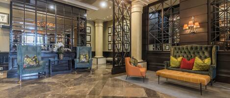 A lobby with a marble floor, a reception desk, and seating areas including a sofa and armchairs.