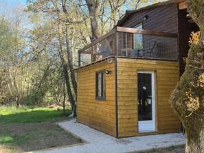 Une cabane en bois dotée d’un balcon, d’une porte et d’une fenêtre.