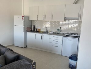 A compact kitchen with white cabinets, a built-in dishwasher, a stove, and a refrigerator. - Stunning Waterfront Holiday at Datça Marina (Muğla)