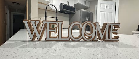 A kitchen with a 'WELCOME' sign on the counter.