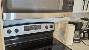 Une cuisine équipée d’un four à micro-ondes, d’un four traditionnel et d’une machine à café.