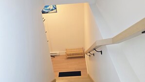 Un escalier en bois mène à une pièce où se trouve un tapis noir au bas de l’escalier.
