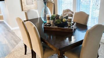 A dining room with a dark wooden table, four chairs, a vase with flowers, and decorative items.