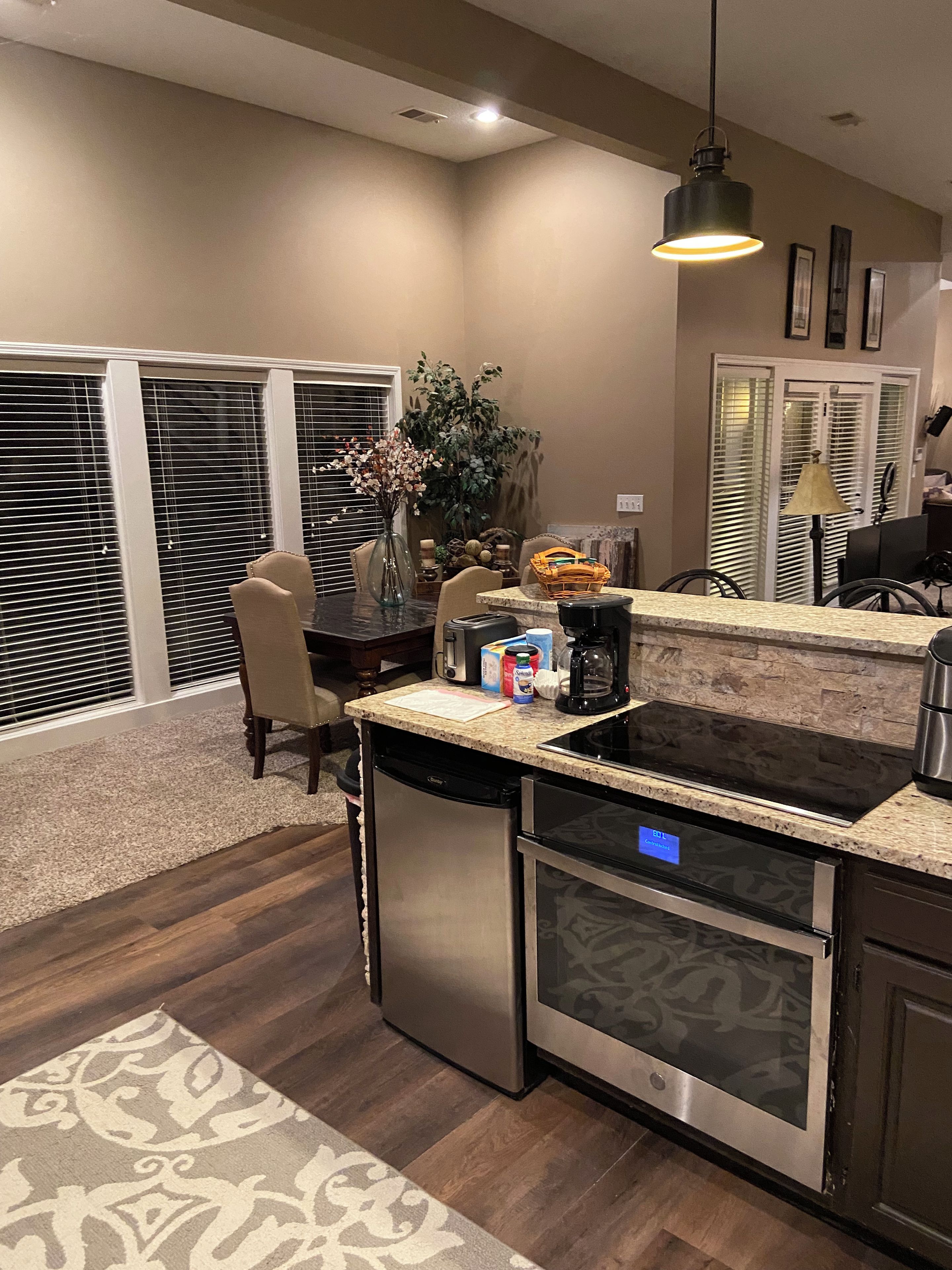 A modern kitchen with a built-in dishwasher, a stove, and a dining area with a chair and a vase of flowers.