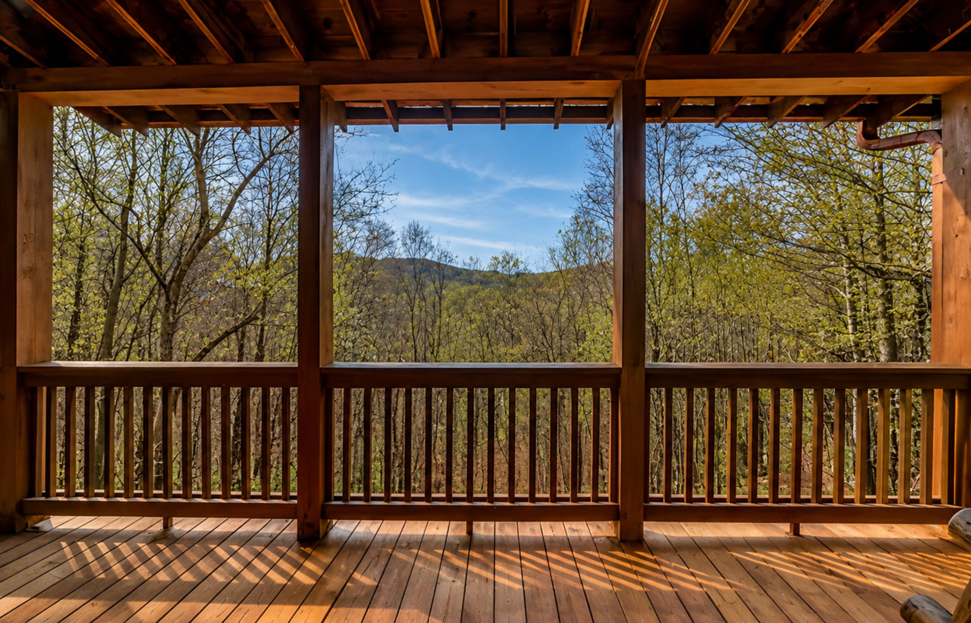 Une terrasse en bois offrant une vue sur une zone boisée et des collines.