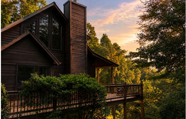 Eine Holzhütte mit Balkon, umgeben von Bäumen.