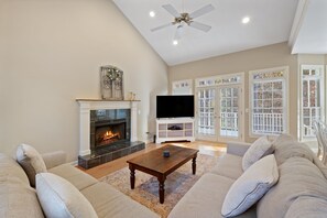 Ein Wohnzimmer mit Kamin, Fernseher und einer Couch.
