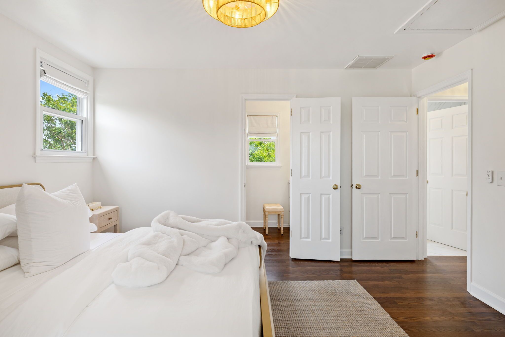 A bedroom with a bed, nightstand, and a view of the outside.