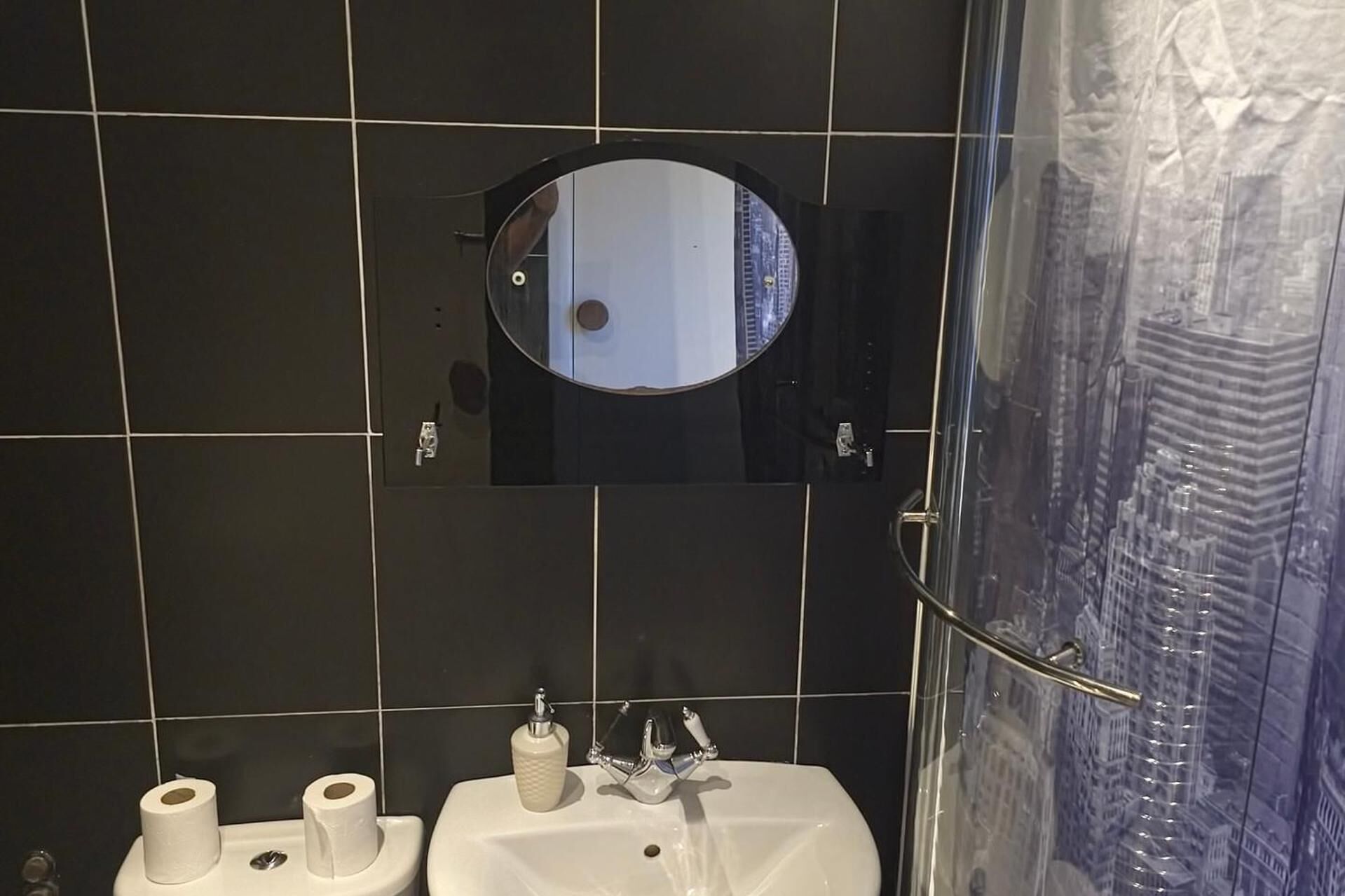 Ein Badezimmer mit Spiegel, Waschbecken und zwei Toilettenpapierrollen.
