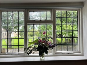 A window with a view of a cemetery and a vase with flowers on the windowsill. - Bell Cottage, a period cottage between the North Yorkshire Moors & Dales (Brompton)