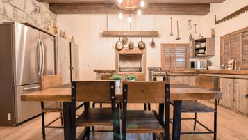 Eine rustikale Küche mit Holztisch und -stühlen, einer Steinwand und einer hängenden Leuchte.