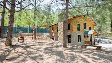 Una cabaña rústica con cimientos de piedra, fachada de madera y un pequeño porche con un columpio.