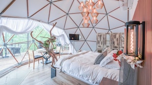 Ein geräumiges Zimmer mit einem großen Bett, einem Essbereich und Blick ins Freie.