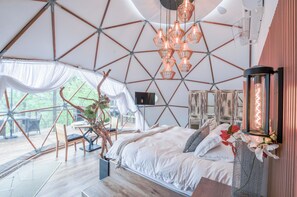 A spacious room with a large bed, a dining area, and a view of the outdoors.