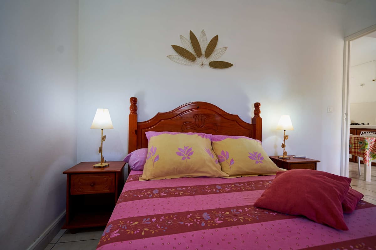 A bed with a wooden headboard, two bedside tables with lamps, and a wall decoration.