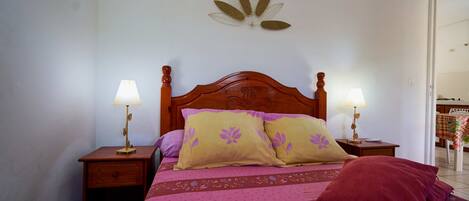 A bed with a wooden headboard, two bedside tables with lamps, and a wall decoration.