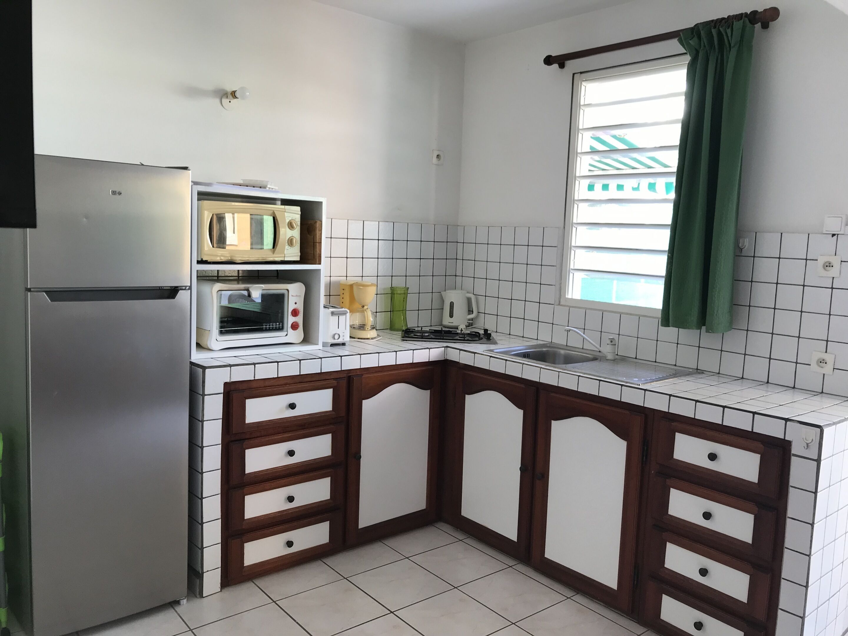 A kitchen with a refrigerator, microwave, toaster, and sink.
