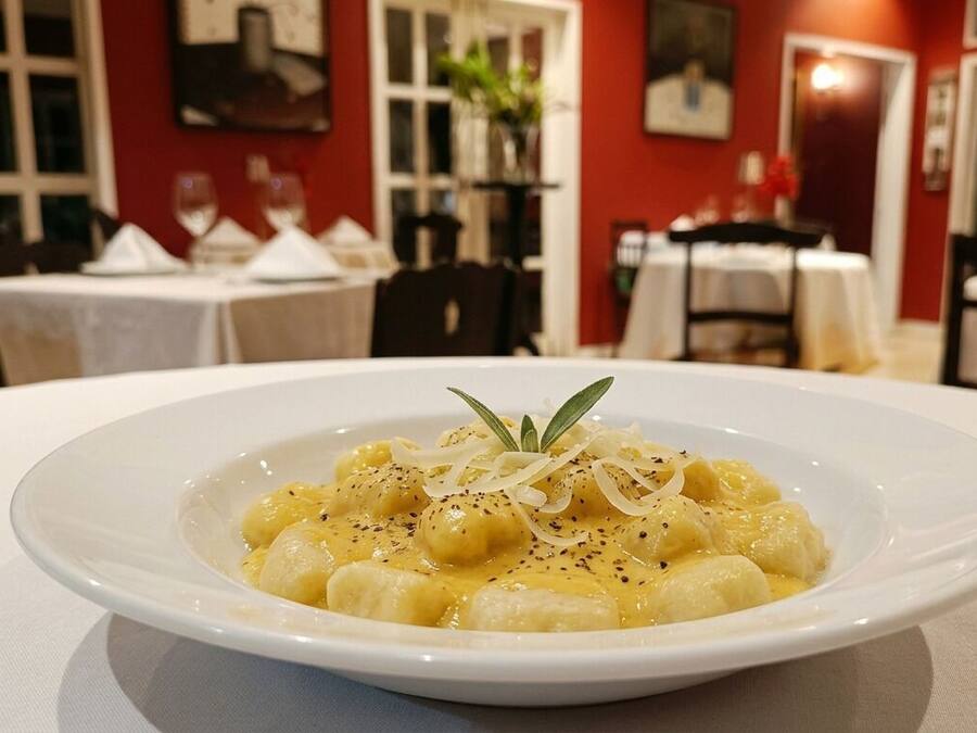 A plate of gnocchi with a garnish on a white table in a restaurant setting.