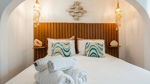 Ein Bett mit hölzernem Kopfteil, zwei Nachttische mit Dekoration und eine Wandleuchte.