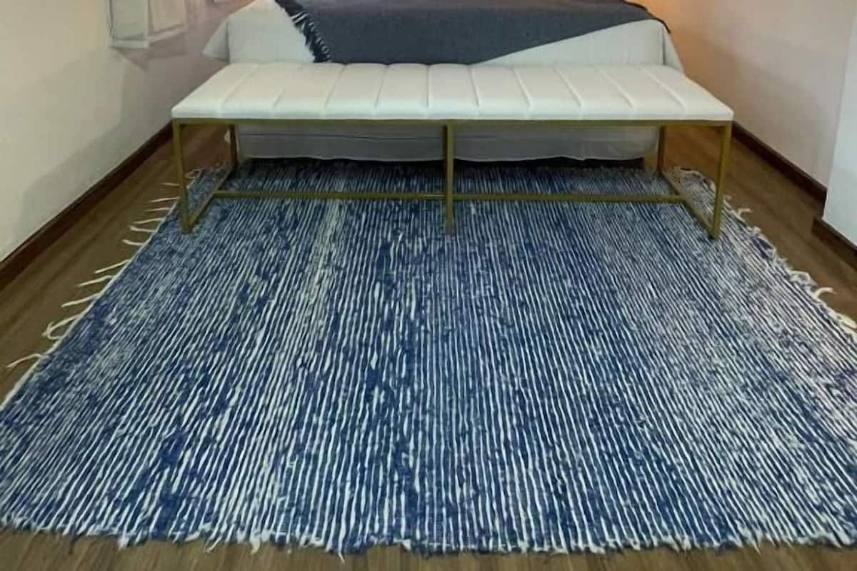 Una habitació amb llit, taules de nit, respatller i aire condicionat, a més d'una catifes amb disseny.
