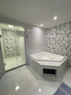 Un baño moderno con ducha envuelta en vidrio, una bañera independiente y piso de baldosas.