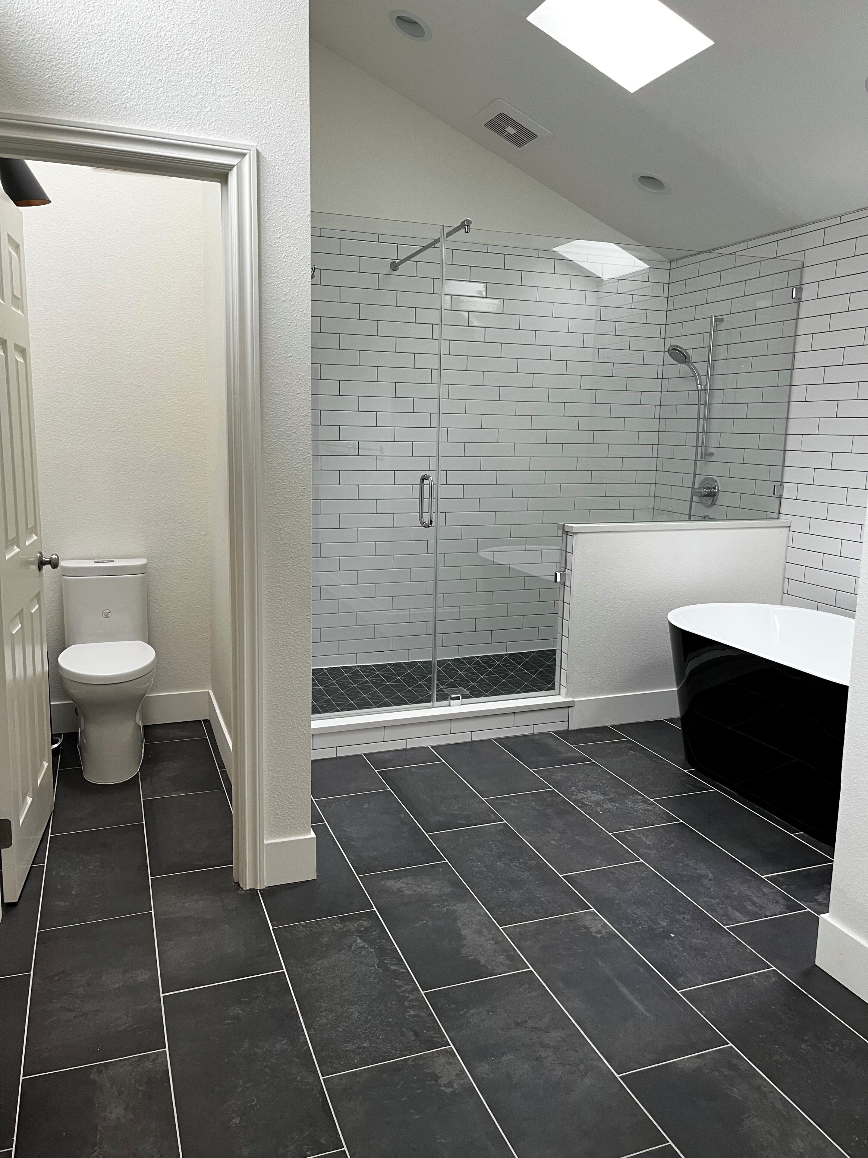 A bathroom with a toilet, a glass-enclosed shower, and a white sink.
