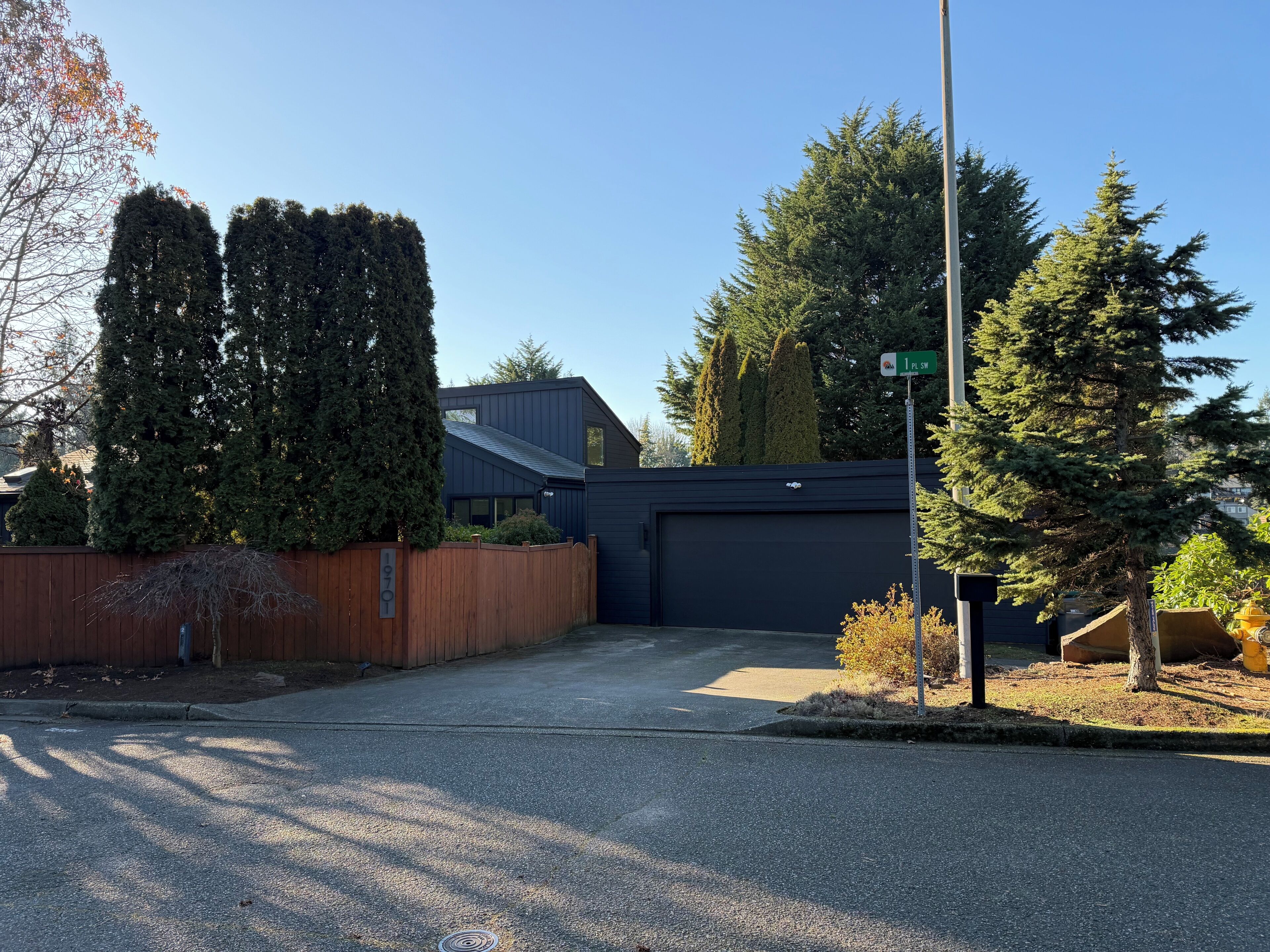 Ein Wohneingang mit Garage, Holzzaun und Straßenschild.