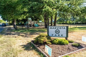 Señal de parque con la leyenda 'MARVISTA PARK' y un parque infantil al fondo.