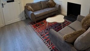 Ein Wohnzimmer mit einer Couch, einem Couchtisch, einem gemusterten Teppich, einem Gemälde und einem Kamin.