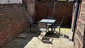 Eine Terrasse mit Steinboden, einem Tisch und Stühlen.