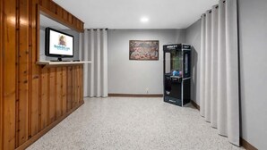 A room with a television on a wooden wall, a framed artwork, and an arcade machine. - Great Home_Sleeps10_ Large Yard_Room for Everyone (Overland Park)