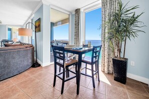 A dining area with a table and chairs, a potted plant, and a view of the ocean. - Palazzo 908 (Panama City Beach)