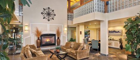 A spacious lobby with a fireplace, wicker furniture, and a view of the reception area.