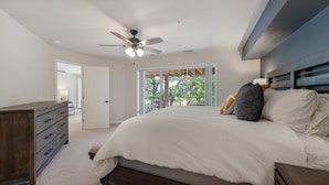 A bedroom with a bed, a dresser, a ceiling fan, and a view through a glass door. - Lakefront living with stunning views and easy pool access, Open-concept space,Close to everything (Lake Ozark)
