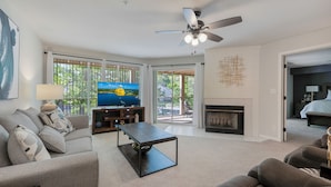 A modern living room with a television, sofa, coffee table, fireplace, and a ceiling fan. - Lakefront living with stunning views and easy pool access, Open-concept space,Close to everything (Lake Ozark)